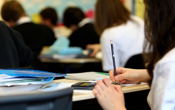 Hands of a student sitting at a desk in school