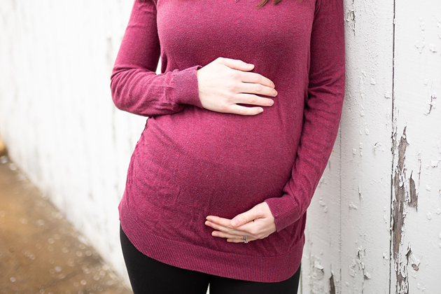 Pregnant woman with a hand on top and below her bumnp