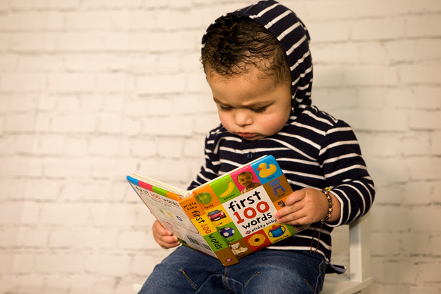 Young boy in a striped hoodie sat looking at a book