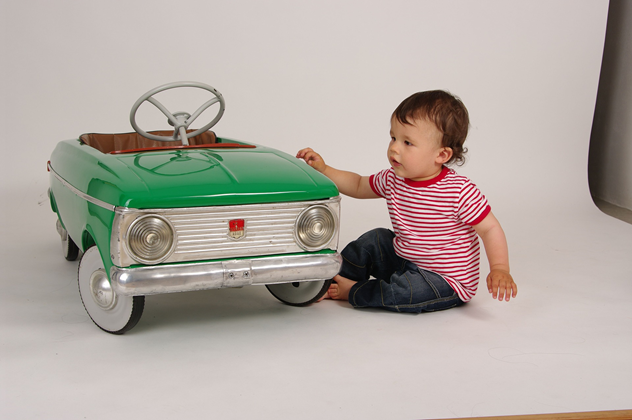 Boy staff on the floor next to a green pedal car