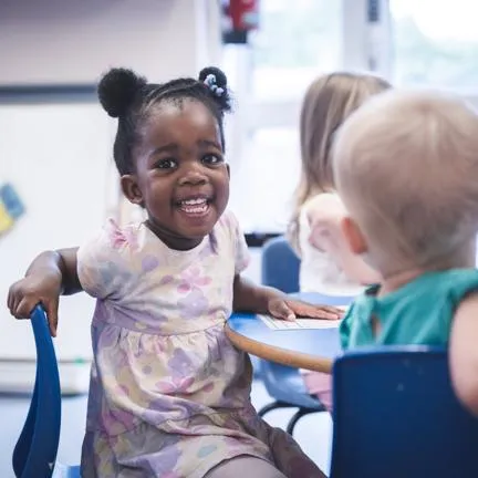 3 young children sat at a round table in a nursery setting