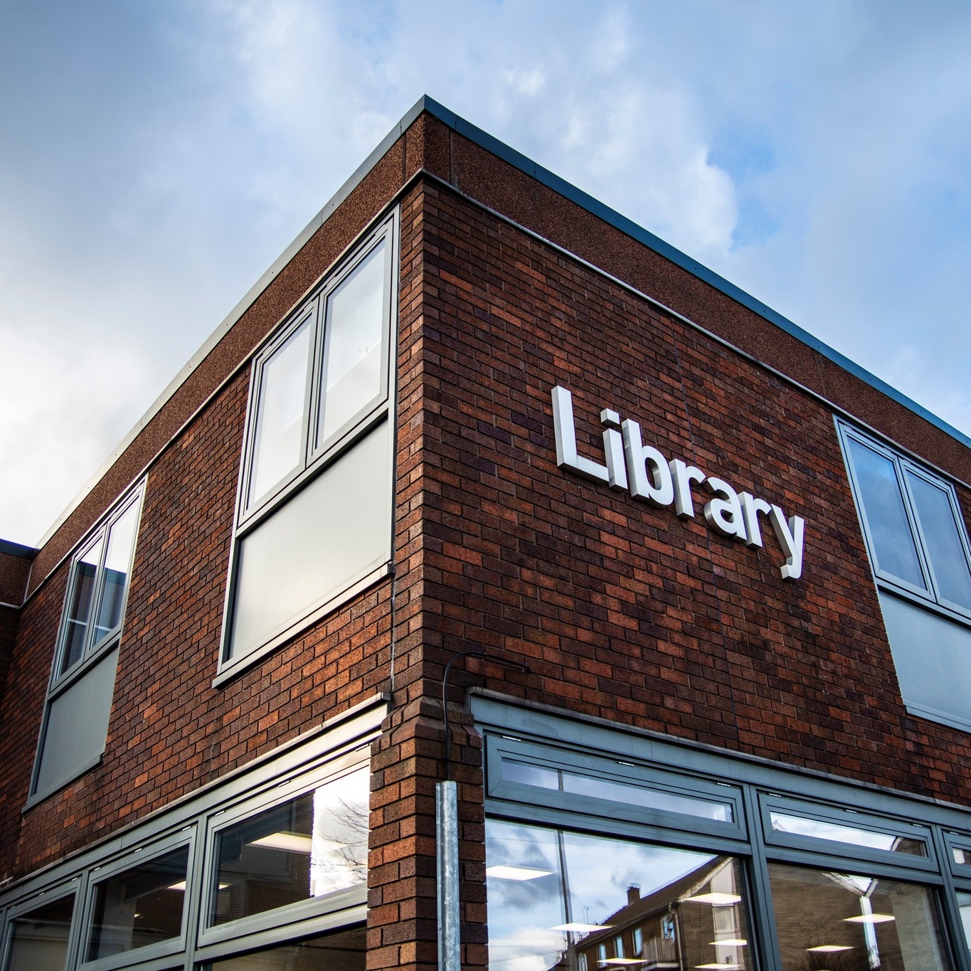 A photo of outside Arnold Library showing the white library sign in front of the orange bricked building.