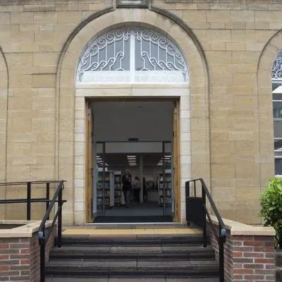Beeston library entrance, three steps leading to wide open double doors under a sandstone archway.