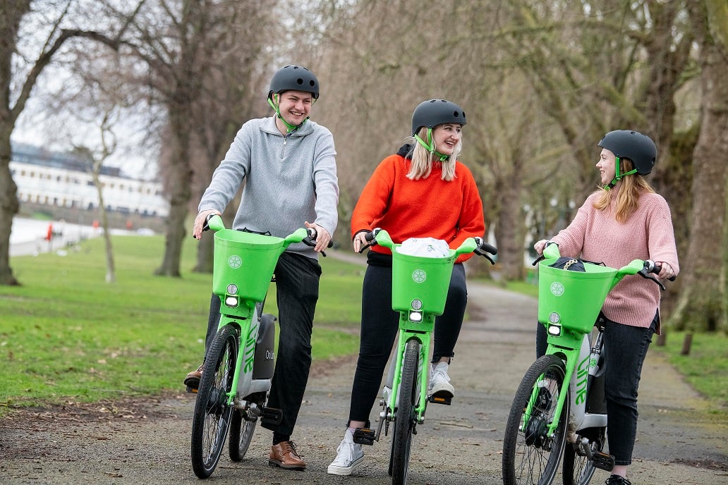 Three people using bright green e-bikes