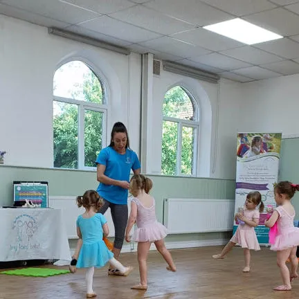 photograph from a ballet session, the leader and the children doing ballet