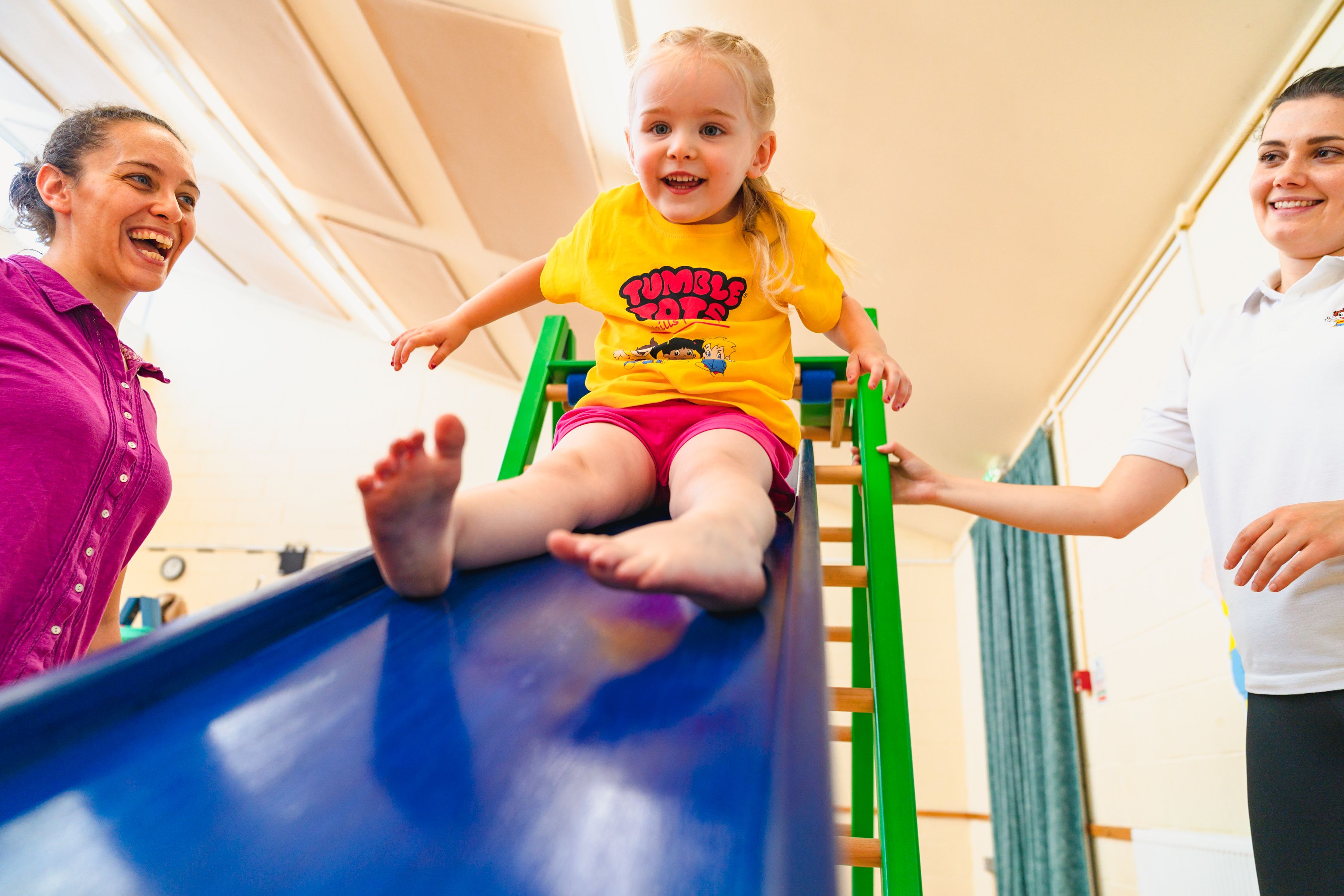 Girl being helped go down a slide