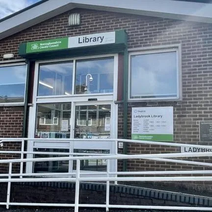 Front view of Ladybrook library entrance, red brick building with an accessibility ramp leading to glass double doors.