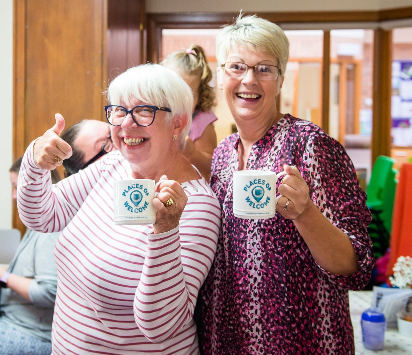 Two people holding coffee mugs that say places of welcome on them