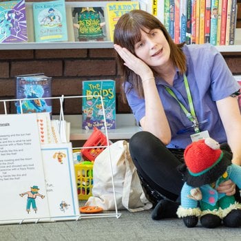 Library staff leading a rattle, rhyme and roll session with song sheets and puppets.