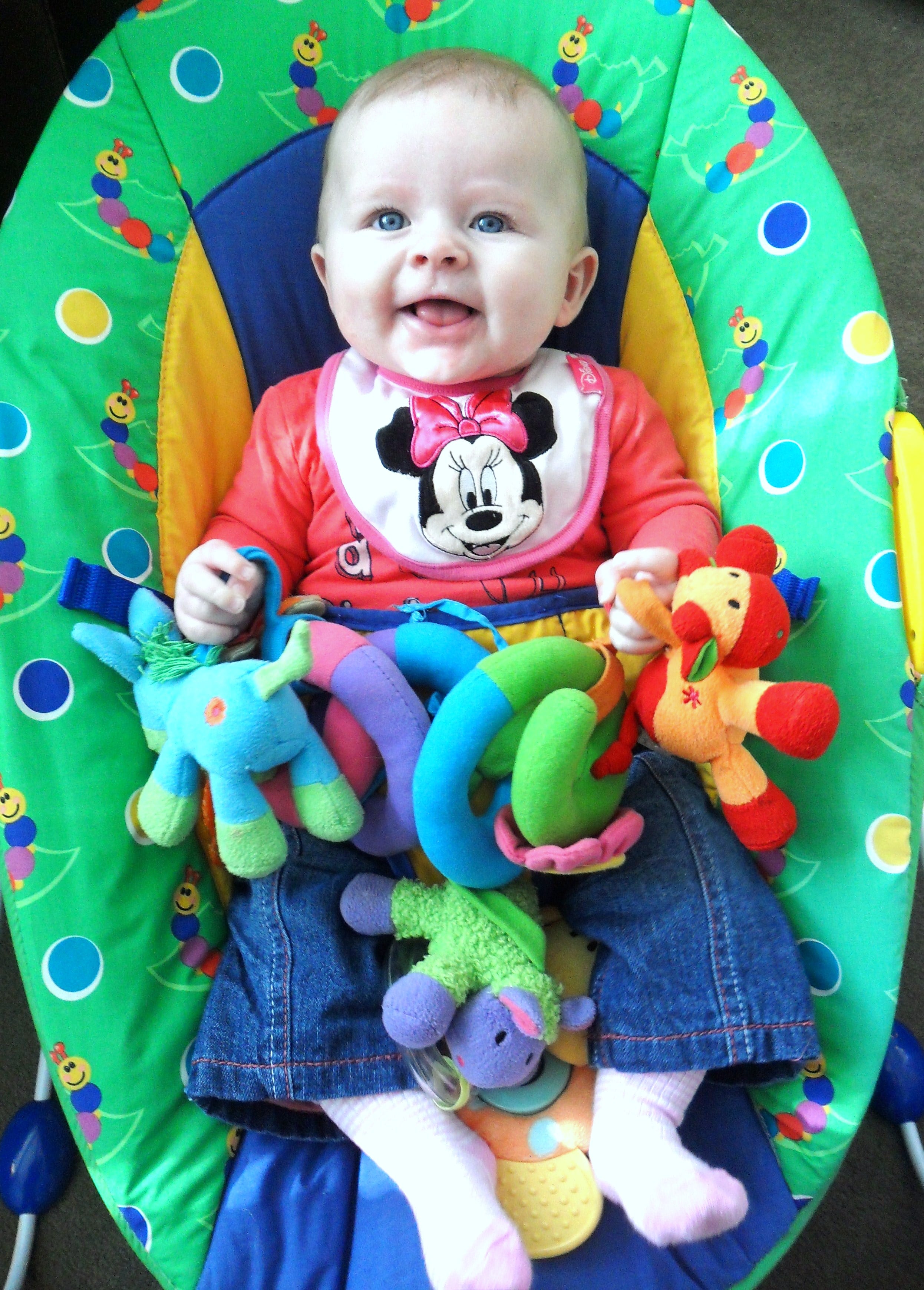 Baby on a baby bouncer with soft toys