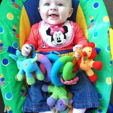 Baby on a baby bouncer with soft toys