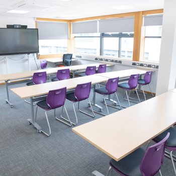 Stapleford Room 1
Bright and spacious with purple chairs and white desks. Large monitor on the far wall.