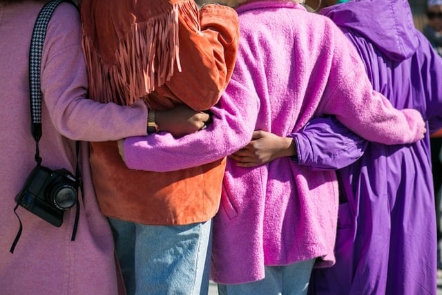 People in Line with arms round each others waists