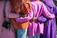 People in Line with arms round each others waists